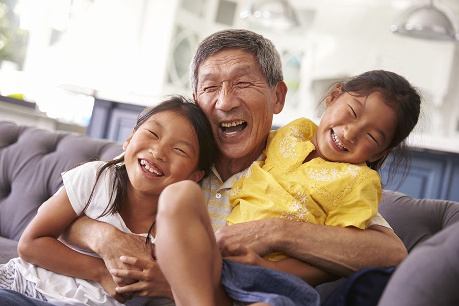 Individual Life Insurance - Portrait of Cheerful Grandfather Playing with His Two Granddaughters in the Living Room